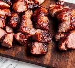 Chopped char siu on a wooden cutting board.